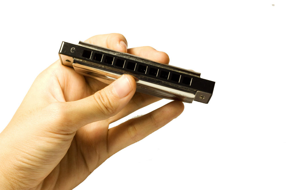 A hand holding a diatonic harmonica