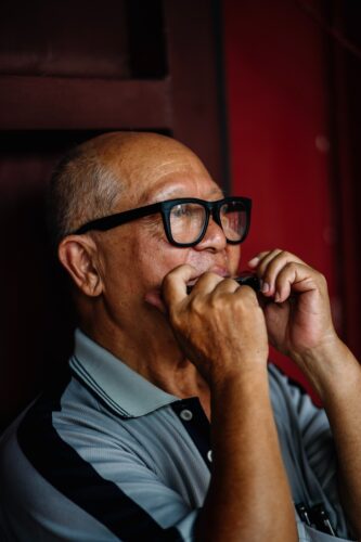 Man in glasses playing a harmonica for beginners