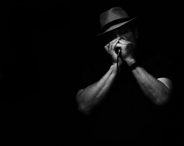 Black and white photo of man playing harmonica