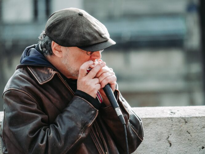 Man in a hat playing harmonica into a mic