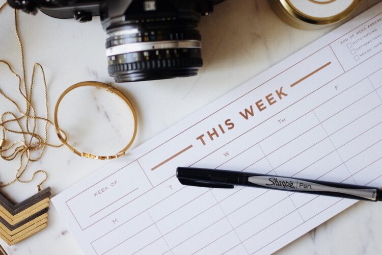 A camera and pen on a weekly planner