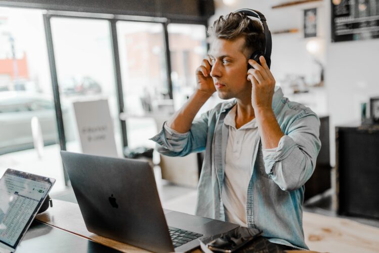 Man with headphones on, working on computer in coffee shop