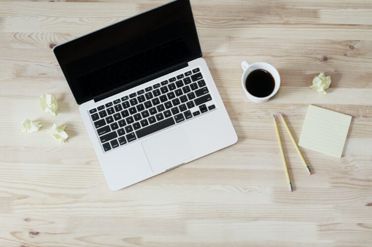 Silver laptop, coffee mug, pencils and paper sitting on table