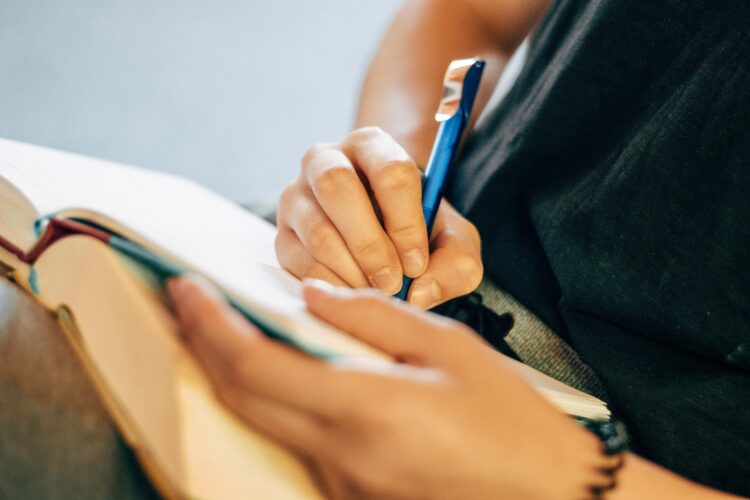 A person holding a notebook and taking notes