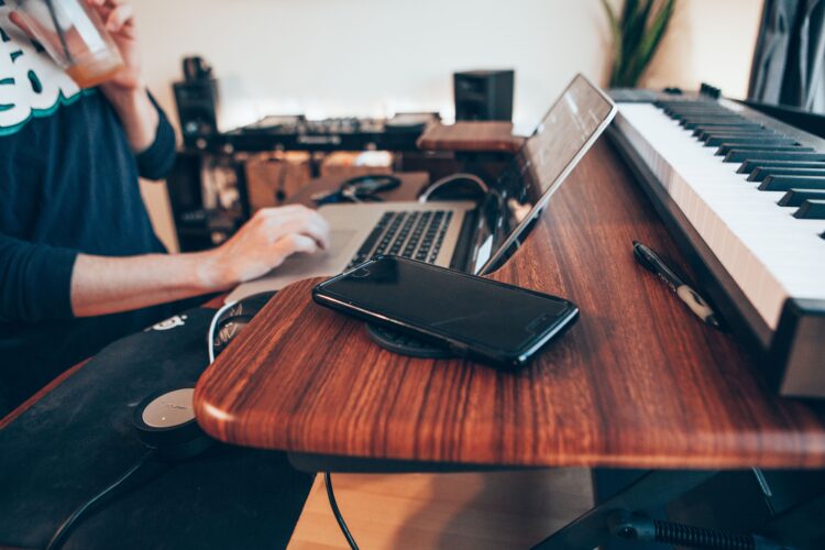 Man sitting at table with laptop, tablet, and table top keyboard